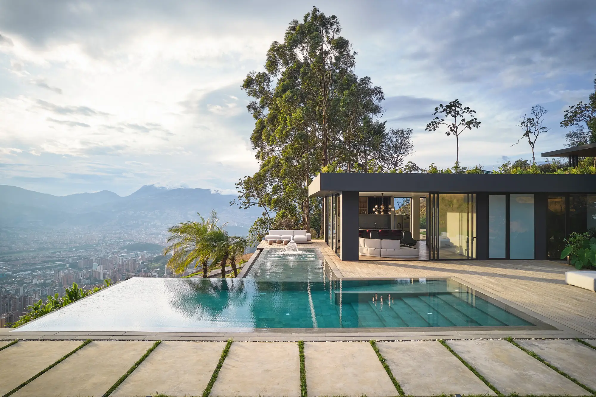 Piscina desbordante sobre la ciudad y la casa de vidrio, proyecto Cinturón Verde.